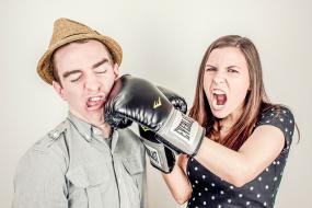Photographie caricaturale d'une femme portant des gants de boxe frappant un homme au visage.