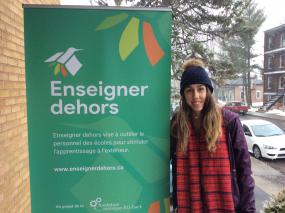 Une personne se tient à côté d'une bannière de "Enseigner dehors".