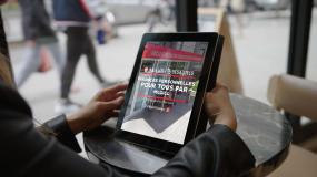 Gros plan sur une tablette électronique entre les mains d'une personne. L'information du cours en ligne est affiché à l'écran.