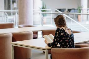Photographie d'une femme assise qui lit un livre.