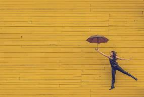 Photographie d'une femme tenant un parapluie ouvert qui semble s'envoler.