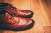 Photographie d'une paire de souliers bruns sur un plancher de bois. La paire est placée de côté, sur la gauche.
