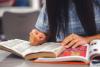 Photographie d'une personne avec deux livres ouverts devant elle.